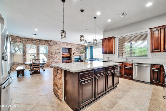 kitchen featuring visible vents, decorative backsplash, appliances with stainless steel finishes, a center island, and a sink