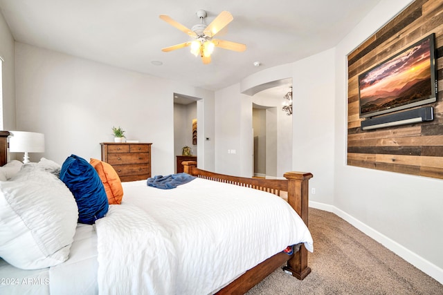 carpeted bedroom featuring baseboards, arched walkways, and ceiling fan