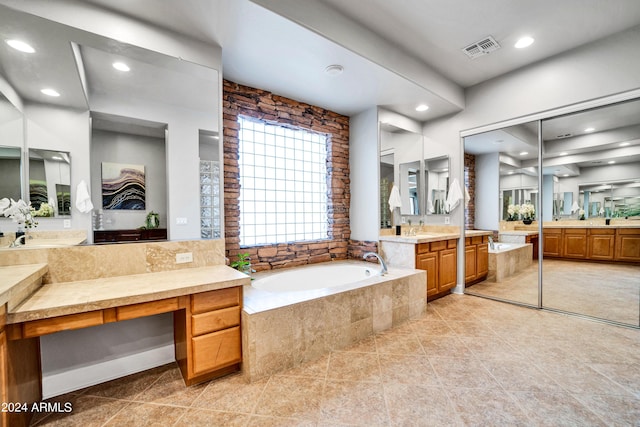 full bathroom with visible vents, two vanities, a bath, and tile patterned floors