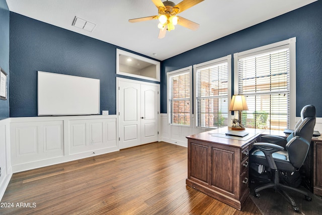 home office featuring ceiling fan, wainscoting, wood finished floors, and visible vents