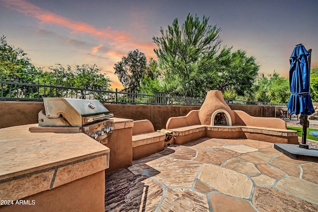 view of patio / terrace featuring fence, exterior fireplace, an outdoor kitchen, and grilling area