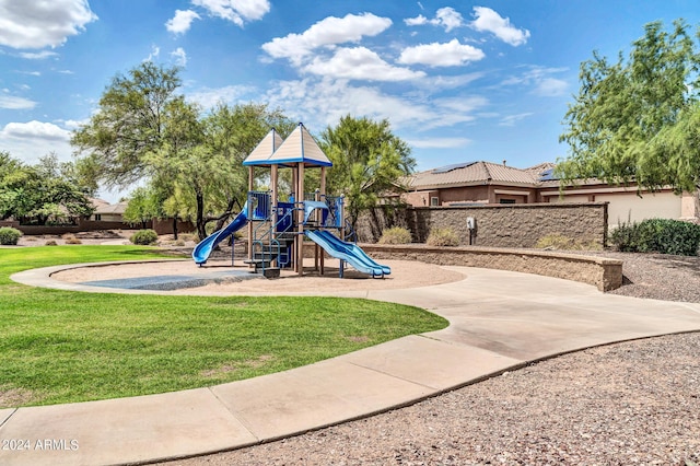 communal playground featuring a lawn and fence