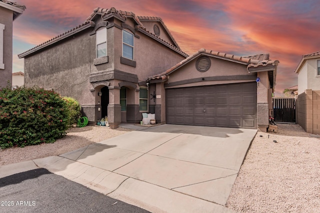 mediterranean / spanish-style house featuring concrete driveway, an attached garage, stucco siding, and a tiled roof