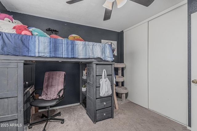 carpeted bedroom with an office area and ceiling fan