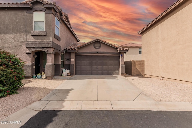 mediterranean / spanish-style house with concrete driveway, stucco siding, a garage, and a tile roof