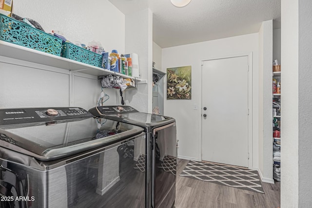 laundry area with washing machine and dryer, wood finished floors, a textured wall, baseboards, and a textured ceiling
