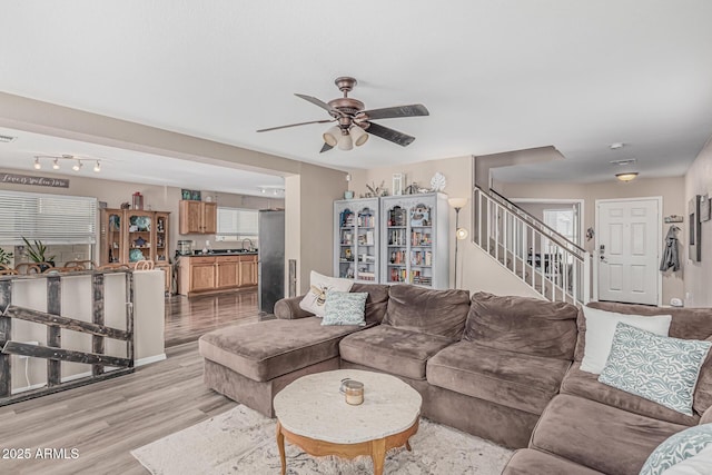 living area featuring light wood finished floors, stairs, and a ceiling fan