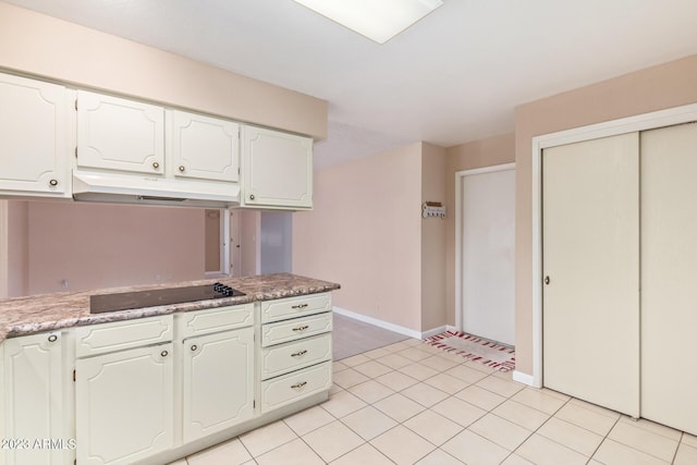 kitchen featuring black electric cooktop, white cabinets, and light tile patterned floors