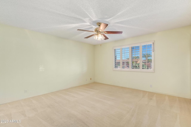 spare room with a textured ceiling, ceiling fan, and light carpet