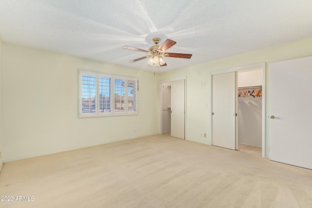 unfurnished bedroom with ceiling fan, light carpet, and a textured ceiling