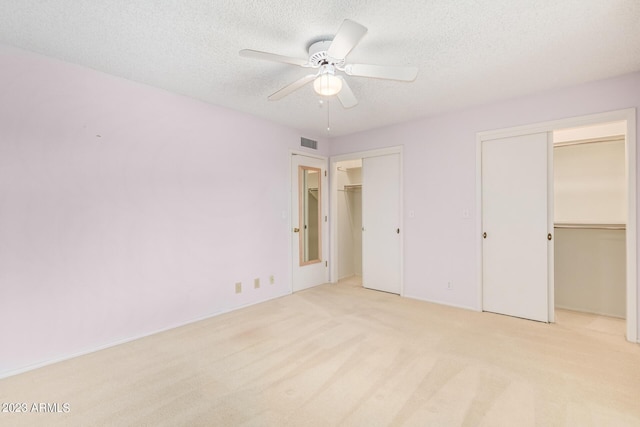 unfurnished bedroom featuring a textured ceiling, ceiling fan, and light carpet