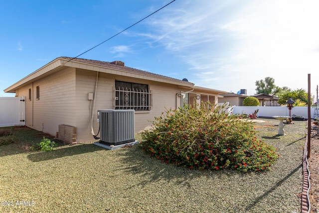 exterior space with central air condition unit and a yard