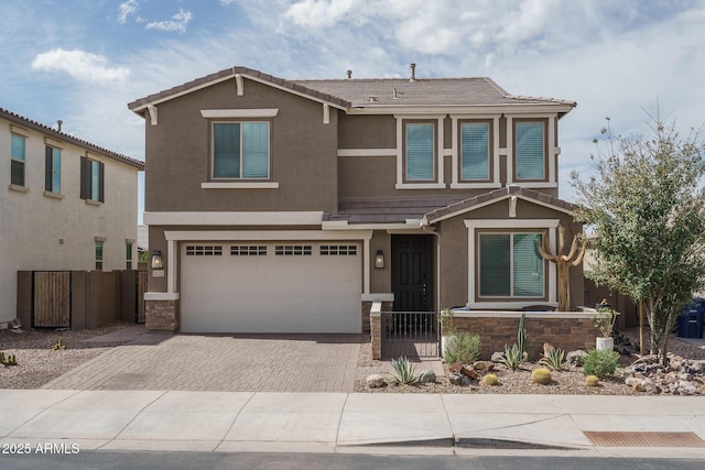 view of front of home featuring a tiled roof, stucco siding, decorative driveway, and fence