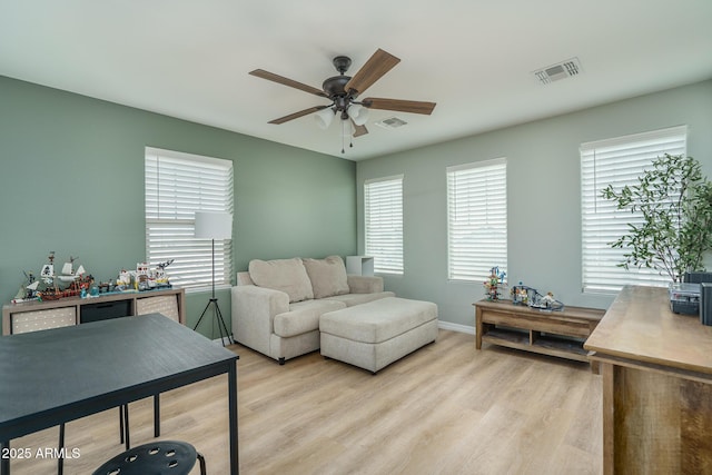 living area with visible vents, baseboards, light wood-type flooring, and a ceiling fan