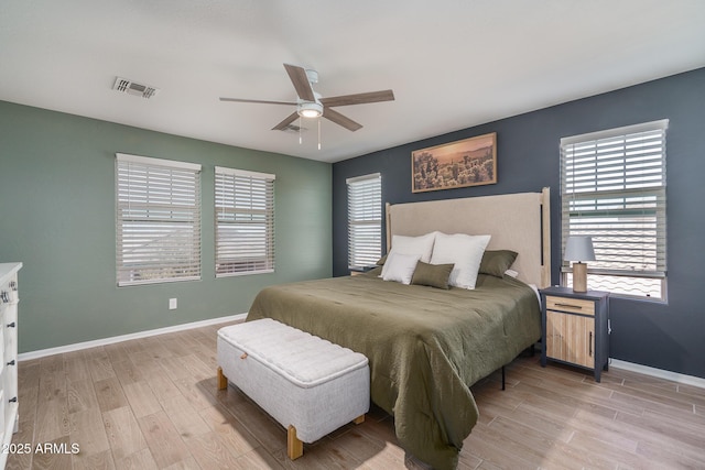 bedroom featuring visible vents, light wood-style flooring, a ceiling fan, and baseboards