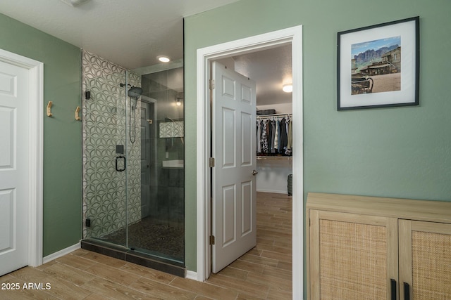 full bath with a walk in closet, a stall shower, and wood tiled floor