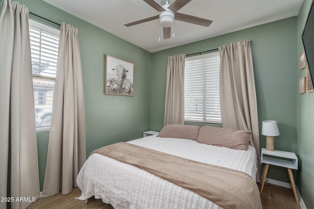 bedroom featuring a ceiling fan, baseboards, and wood finished floors