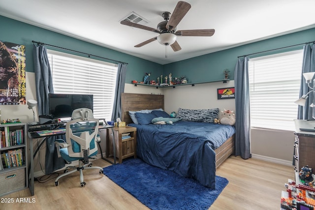 bedroom featuring a ceiling fan, wood finished floors, visible vents, and baseboards