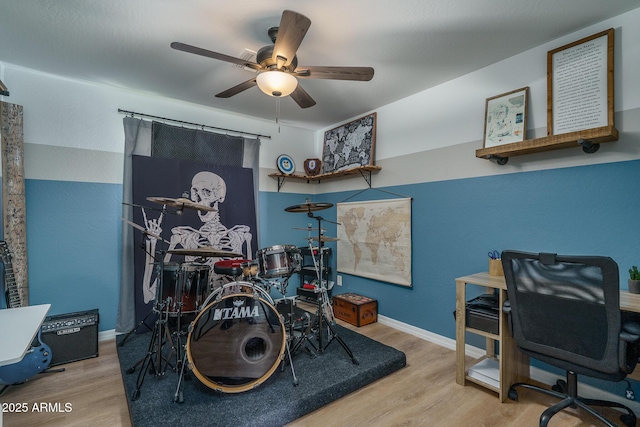 interior space with baseboards, wood finished floors, and a ceiling fan