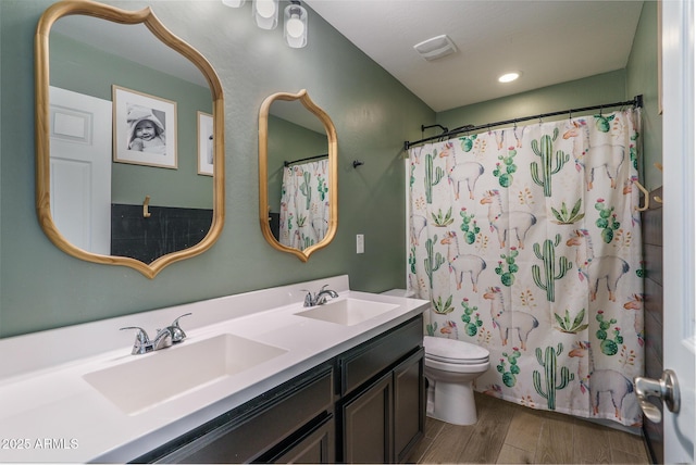 full bathroom with a sink, toilet, wood finished floors, and double vanity