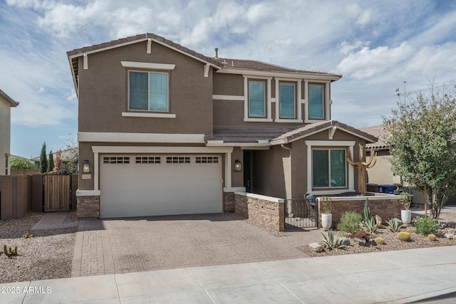 craftsman-style home featuring a gate, decorative driveway, a garage, and stucco siding