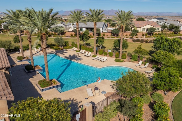 community pool featuring a patio, fence, a mountain view, and a residential view