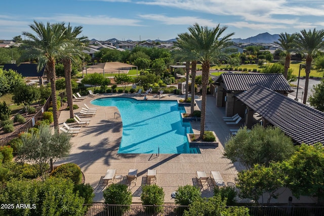 pool with a patio area, a mountain view, and fence