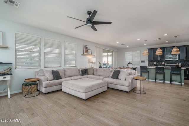 living area with light wood-type flooring, visible vents, ceiling fan, and recessed lighting