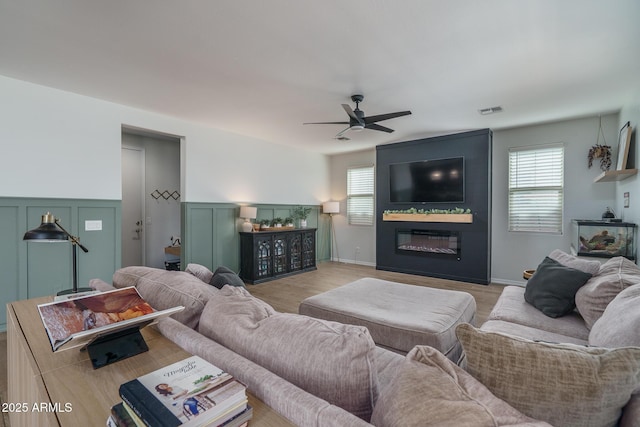 living area with plenty of natural light, a ceiling fan, visible vents, and a large fireplace