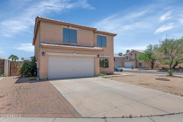 mediterranean / spanish house featuring concrete driveway, stucco siding, a garage, a tiled roof, and fence