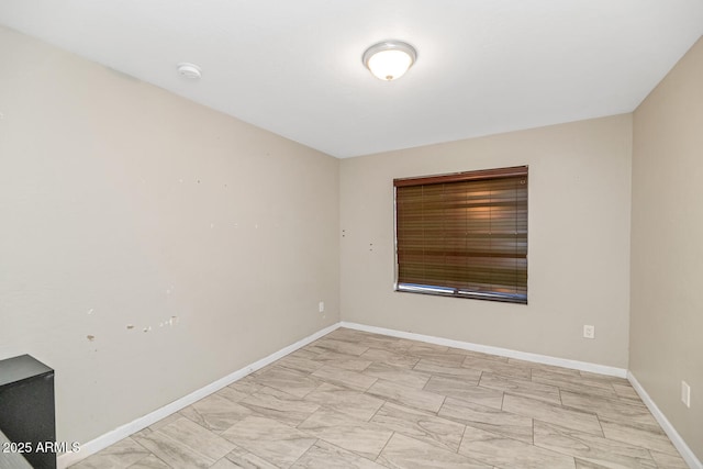 spare room featuring baseboards, a smoke detector, and light marble finish floors
