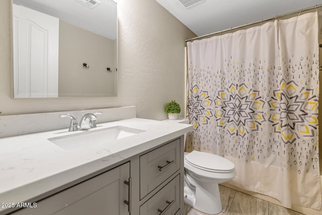 full bathroom with toilet, vanity, a shower with shower curtain, and a textured wall