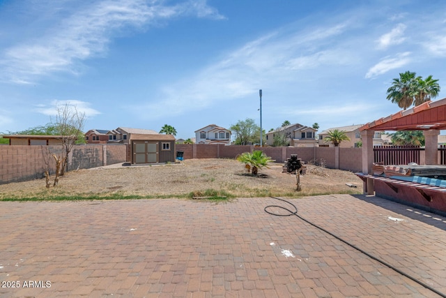 fenced backyard with a storage unit, a patio, an outbuilding, and a residential view