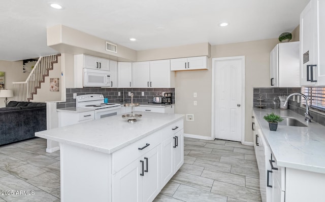 kitchen with white appliances, open floor plan, a sink, light stone counters, and tasteful backsplash