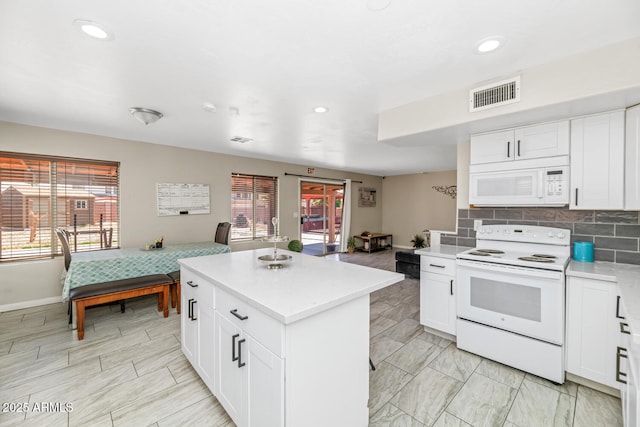 kitchen featuring white appliances, light countertops, a kitchen island, recessed lighting, and white cabinets