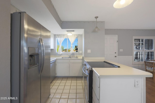 kitchen featuring sink, hanging light fixtures, light tile patterned floors, white cabinetry, and stainless steel appliances