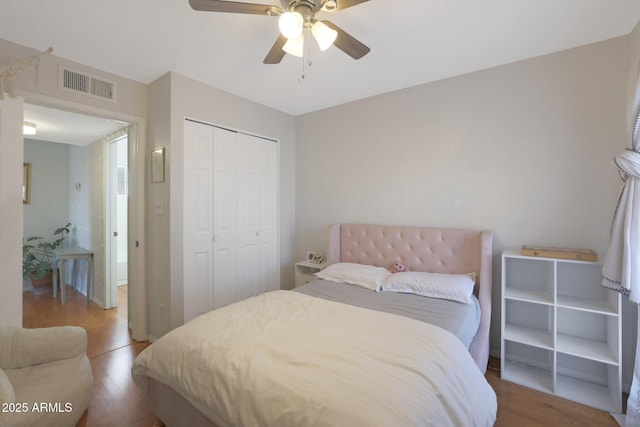 bedroom with ceiling fan, a closet, and wood-type flooring