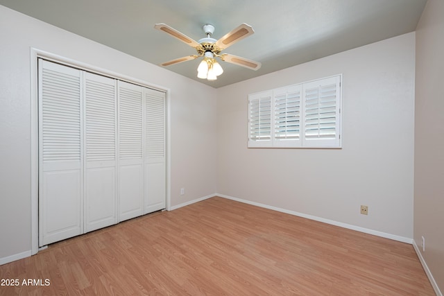 unfurnished bedroom featuring light wood-style floors, a ceiling fan, baseboards, and a closet