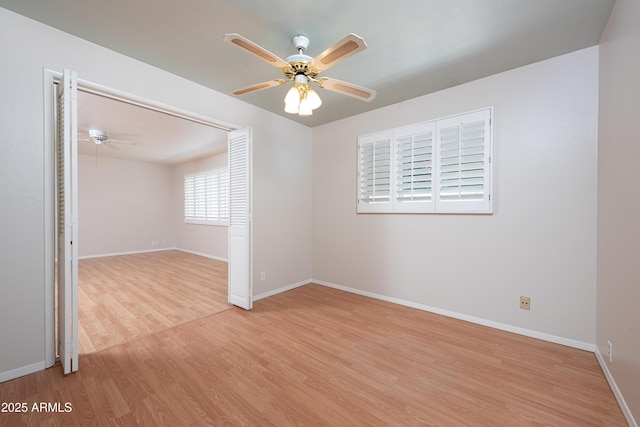 spare room with light wood-type flooring, ceiling fan, and baseboards