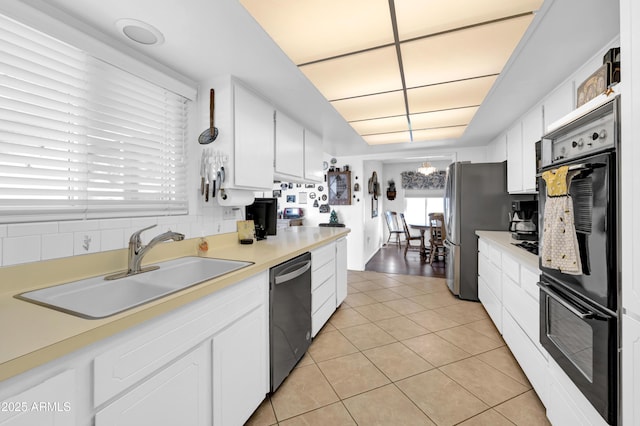 kitchen with sink, stainless steel appliances, light tile patterned floors, and white cabinetry