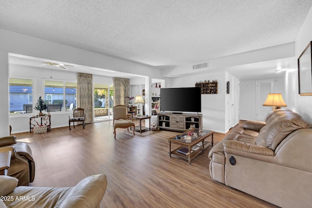 living room with hardwood / wood-style flooring, a textured ceiling, and ceiling fan