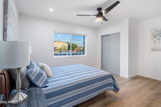 bedroom with light hardwood / wood-style floors, a closet, and ceiling fan