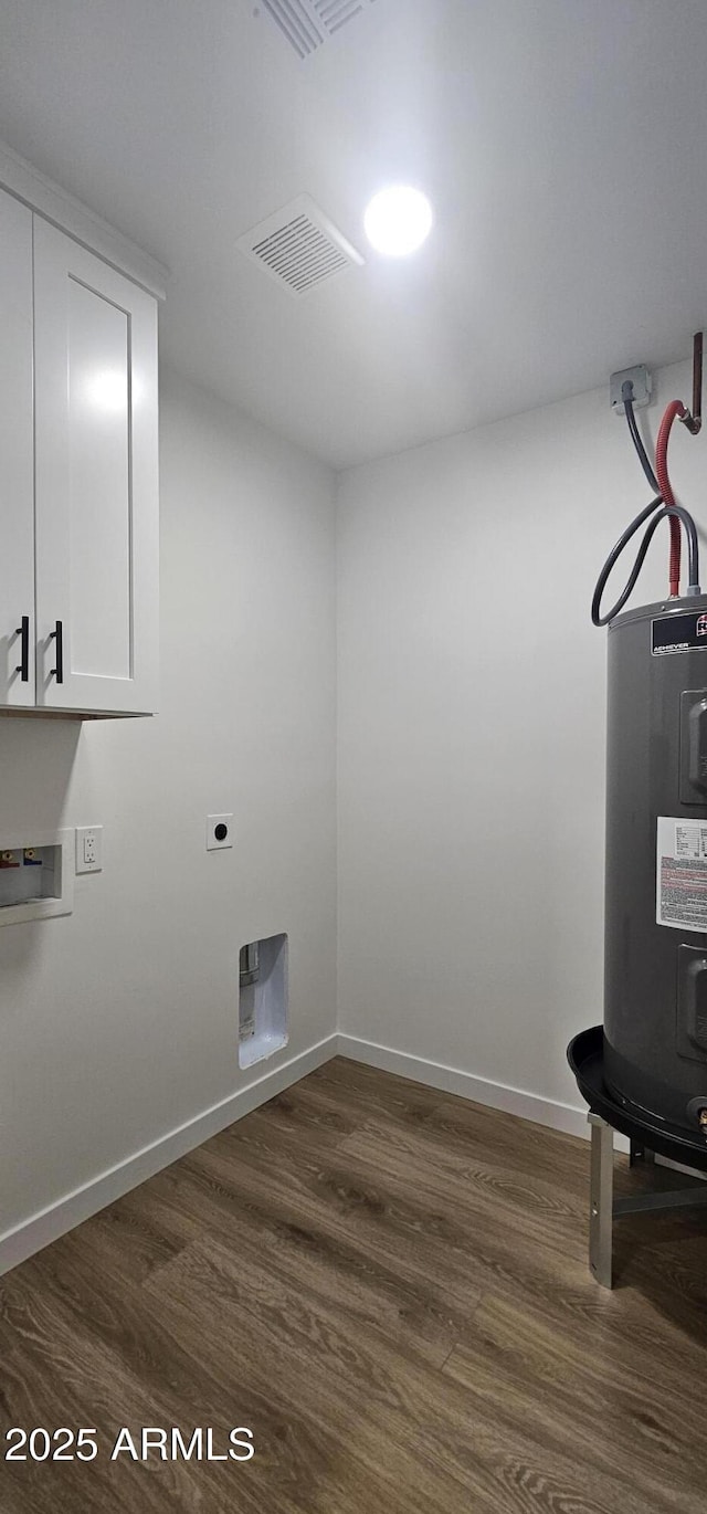 washroom featuring dark hardwood / wood-style flooring, electric water heater, hookup for a washing machine, and cabinets