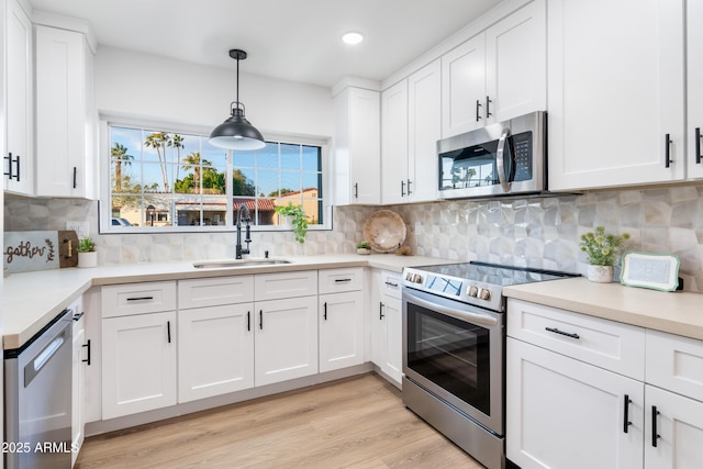 kitchen featuring tasteful backsplash, white cabinetry, appliances with stainless steel finishes, and sink