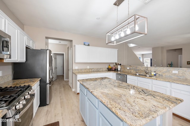 kitchen with appliances with stainless steel finishes, white cabinetry, pendant lighting, and sink