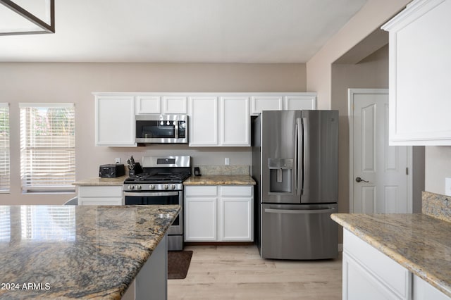 kitchen featuring white cabinets, light stone countertops, stainless steel appliances, and light hardwood / wood-style flooring