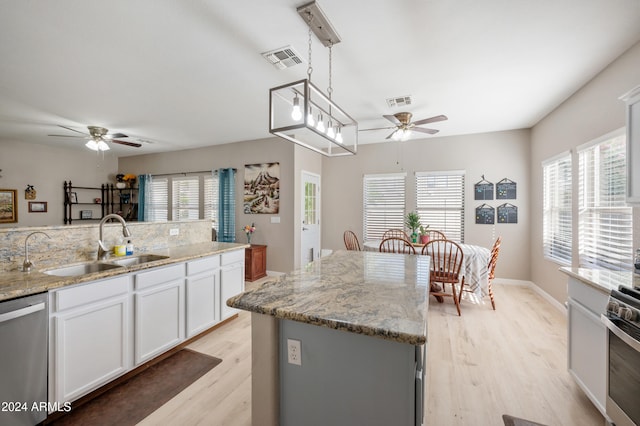 kitchen with light hardwood / wood-style floors, a center island, white cabinetry, hanging light fixtures, and appliances with stainless steel finishes