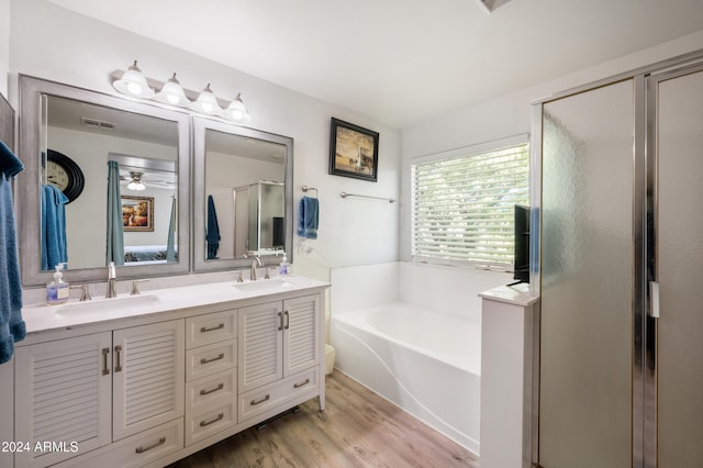 bathroom featuring hardwood / wood-style flooring, vanity, and separate shower and tub