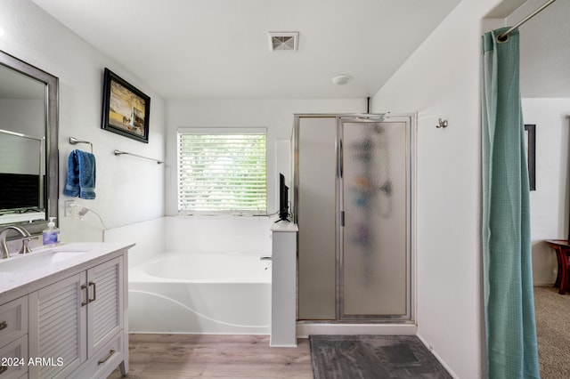 bathroom featuring vanity, wood-type flooring, and shower with separate bathtub