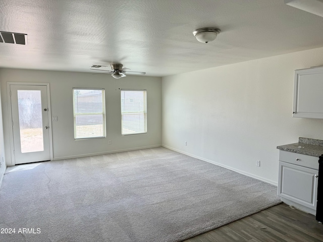 unfurnished living room with ceiling fan, a textured ceiling, and light wood-type flooring